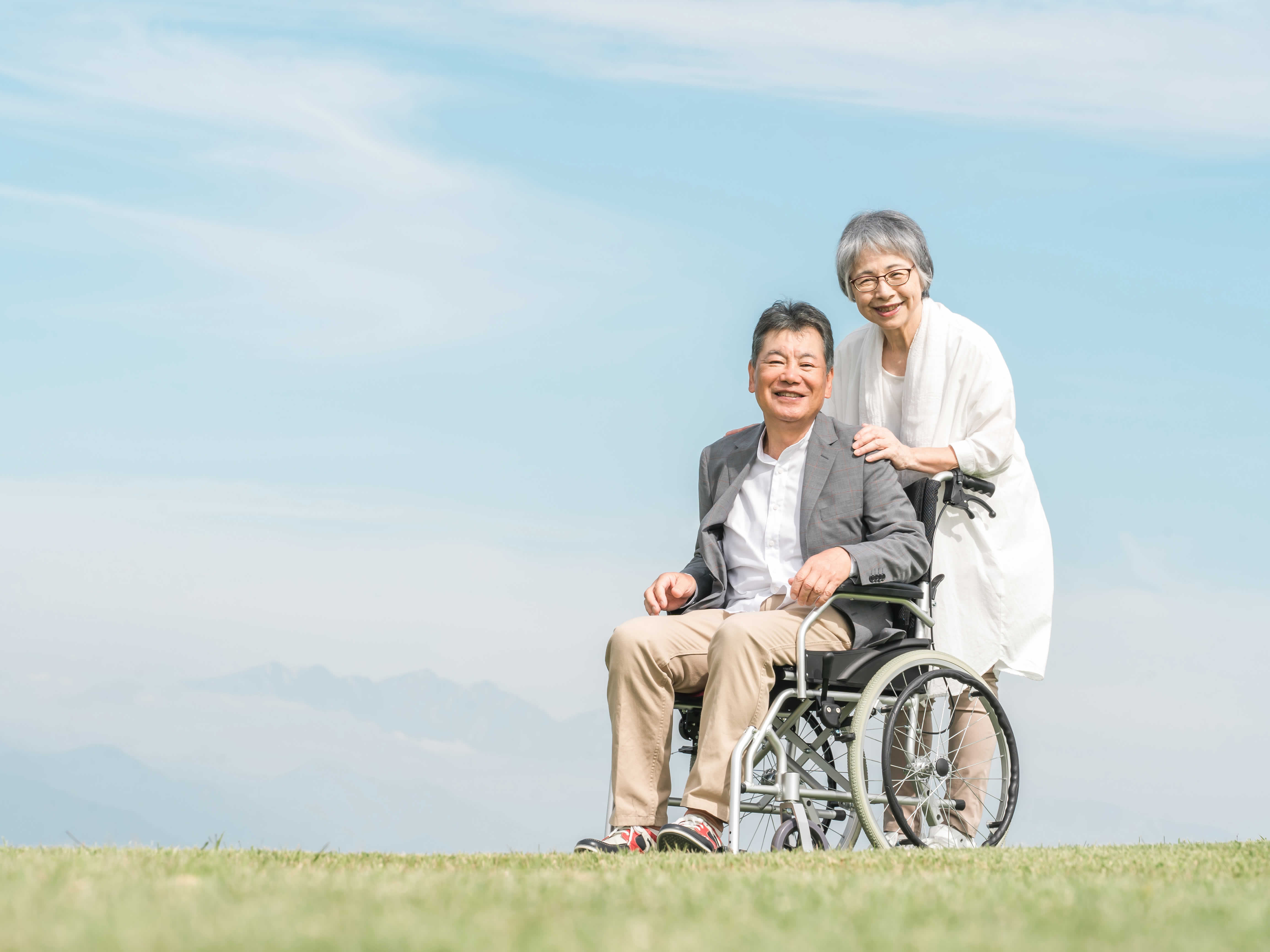 車椅子に座る男性と寄り添う女性